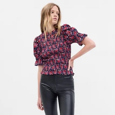 A woman wearing a floral top and black pants