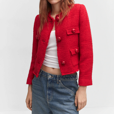 A woman wearing a red pocket tweed jacket with a white top and denim trousers