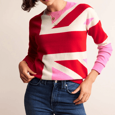 A woman wearing a sweater with the British flag (in red, pink, and white) and blue jeans