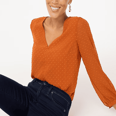 A woman wearing a orange V-neck top and denim pants