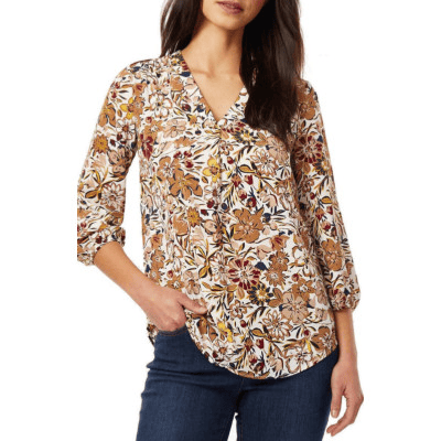 A woman wearing a brown floral top and denim pants