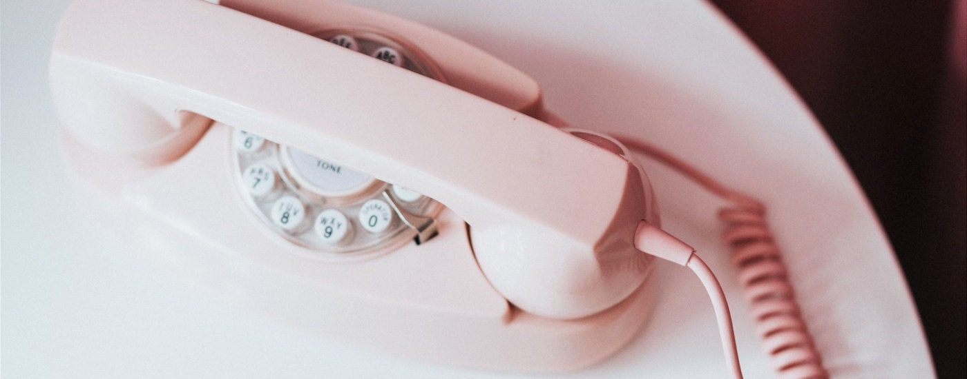 pink rotary phone sits on table