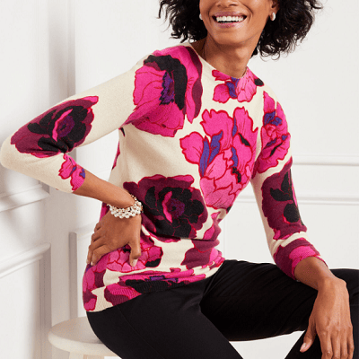 A woman wearing a floral printed sweater and black pants