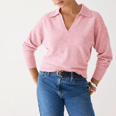 A woman wearing a pink v-neck sweater and denim jeans