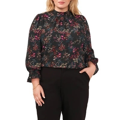 A woman wearing a black floral printed long sleeve blouse and black trouser