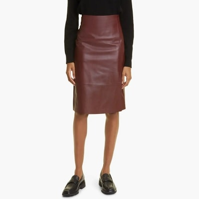A woman wearing a black turtleneck and brown leather skirt; she is wearing loafers with her skirt