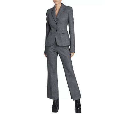 woman wears gray pants suit; the pants are ankle-length and she wears them with shiny black boots with a large platform sole