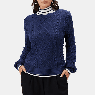 woman wears organic cotton sweater with a striped turtleneck underneath it; the sweater has an interesting pattern on the front
