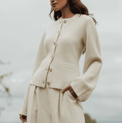 woman wears beige cardigan jacket with 7 buttons, a shaped waist, and wide sleeves