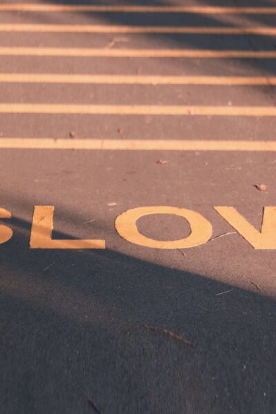 marking on road reads SLOW; there are yellow lines above it