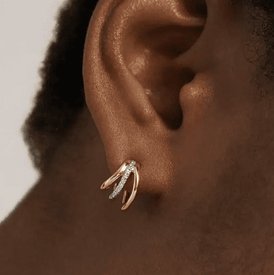 Black woman wears gold huggie earrings with diamond accents