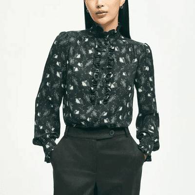 A woman wearing a black long sleeve owl-print top and black trouser