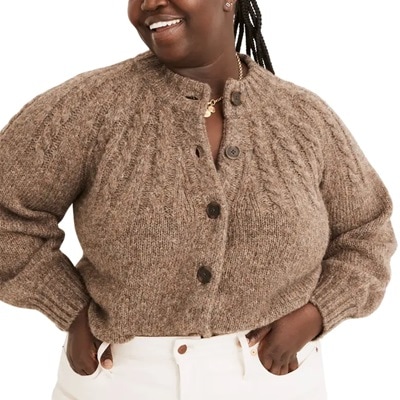 A woman wearing a brown cardigan and white pants