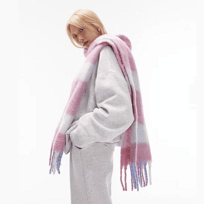 blonde Asian woman wears pink and white blanket scarf; she is also wearing a gray sweatsuit