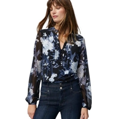 A woman wearing a black-and-blue floral top and blue jeans 