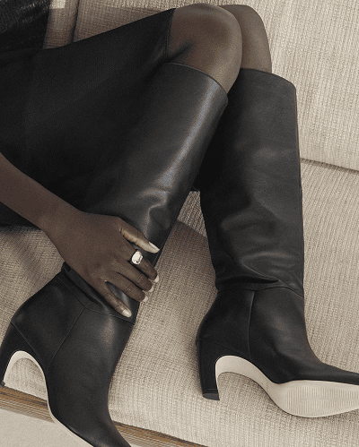 Black woman wears knee-high boots with black skirt and black pantyhose