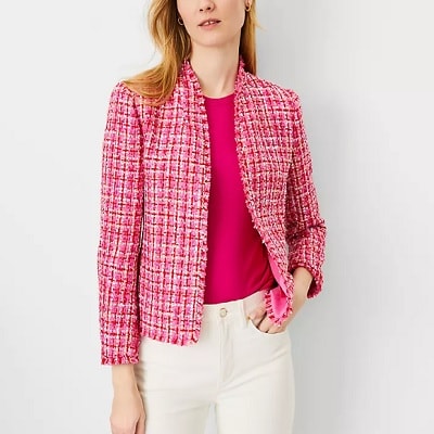 A woman wearing a pink tweed blazer with pink blouse and white pants