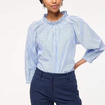 A woman wearing a blue and white stripe blouse and navy blue trouser