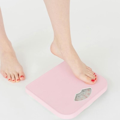 woman with red toenails steps on pink scale