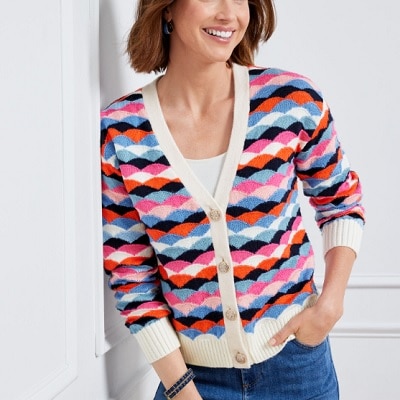 A woman wearing a colorful striped cardigan, white top, and blue jeans