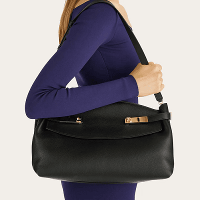 woman carries black Ferragamo Hug Pouch Bag