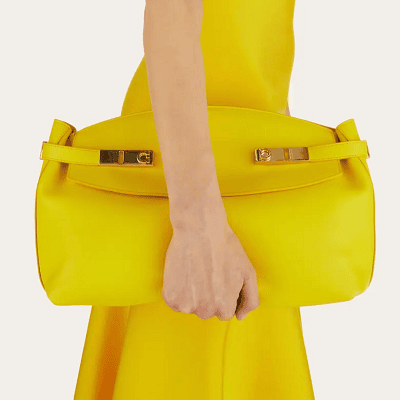 woman holds yellow Ferragamo Hug Pouch Bag