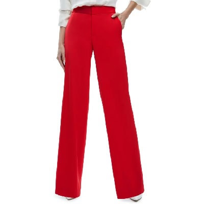 A woman wearing red wide leg pants and white heels