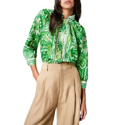 A woman wearing a green floral printed top and khaki-colored pants