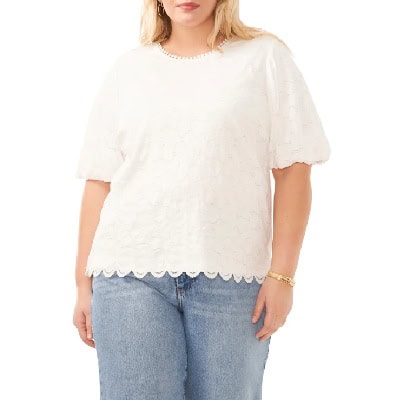 A woman wearing a white oversized lace top and jeans