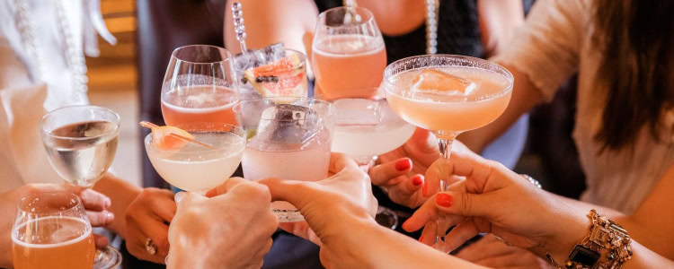 a group of people toast with summer cocktails, wine, and beer
