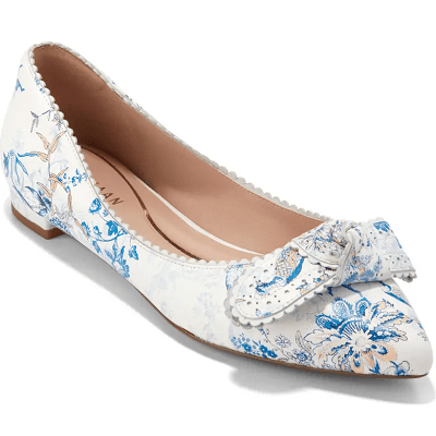 white ballet flat skimmer in a white and blue peacock print; there is a flat bow across the front of the shoe