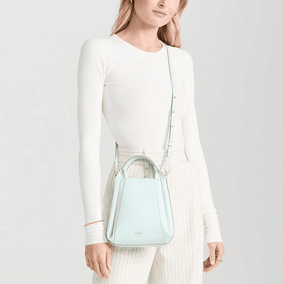 woman wears white/cream outfit with a vertical, mini, mint green crossbody tote 