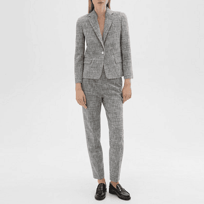 professional young woman wears a light gray canvas tweed suit with black loafers