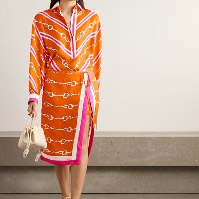 A woman wearing a orange print Gucci silk dress and carrying an off-white Loewe bag 