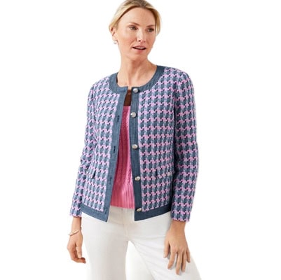 A woman wearing a blue tweed jacket, pink top, and white pants