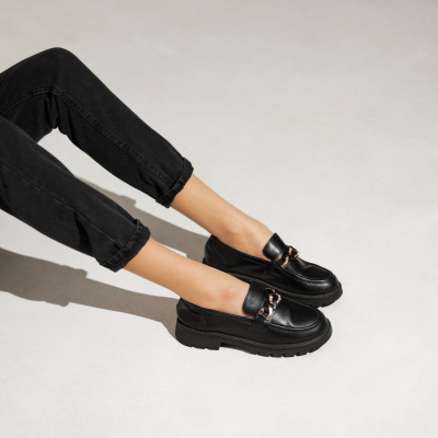 woman lounges while wearing black loafers and black work pants