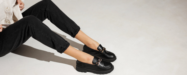 woman lounges while wearing black loafers and black work pants