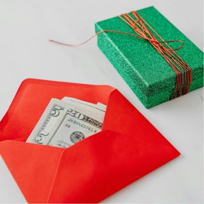 red envelope filled with cash; a green sparkly wrapped gift is nearby