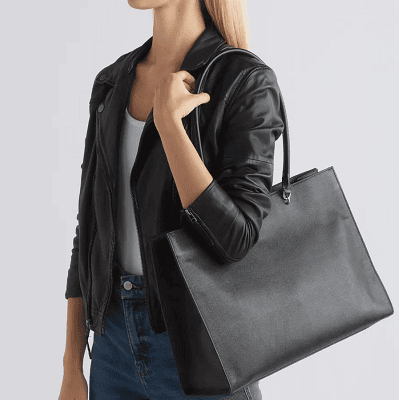 woman carries black leather tote on her shoulder