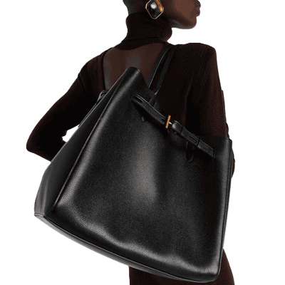 Black woman wearing brown turtleneck carries large black tote bag