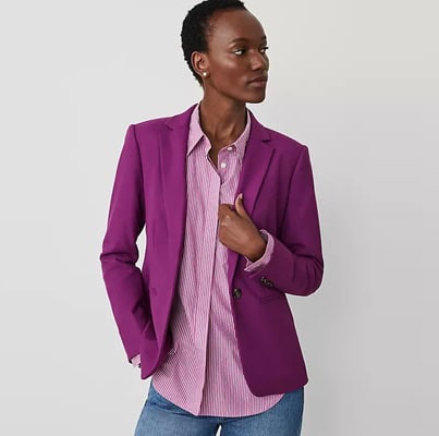 a woman wearing a purple blazer, purple-and-white striped blouse, and blue jeans