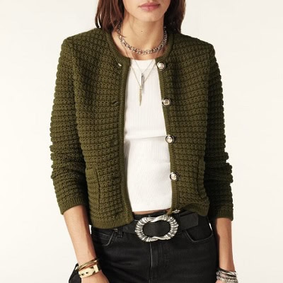 A woman wearing a white blouse and green cardigan jacket with black pants and belt