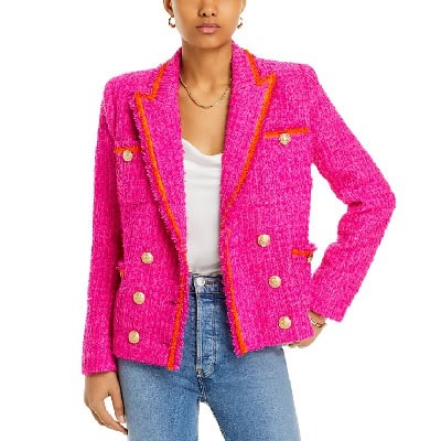 A woman wearing a bright pink blazer with white top and denim pants