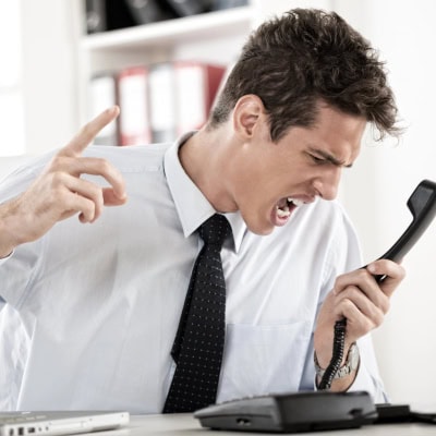 young businessman screams into a phone; he looks like he would be a difficult person to work with