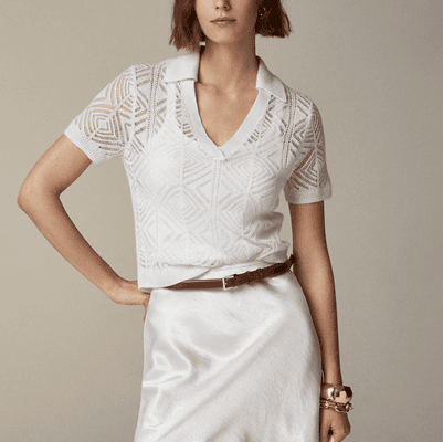 woman wears "cashmere lace pointelle" sweater in white with a white tank top beneath it and a white silk skirt