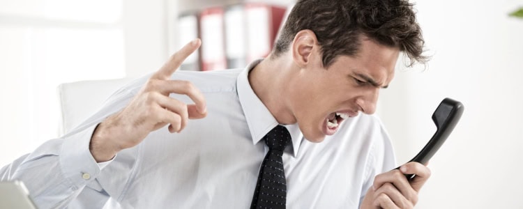 young businessman screams into a phone; he looks like he would be a difficult person to work with