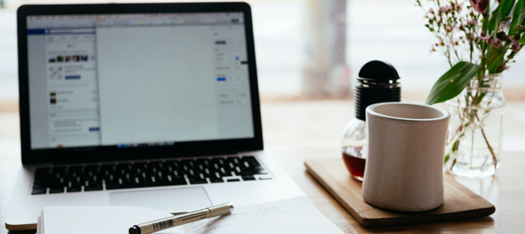 laptop computer with open notebook and cup of coffee