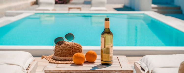 luxury pool that Kat would buy if she won the lottery; there is a bottle of wine, straw hat, sunglasses, and two oranges in the foreground because I guess I'd be drinking out of the bottle?