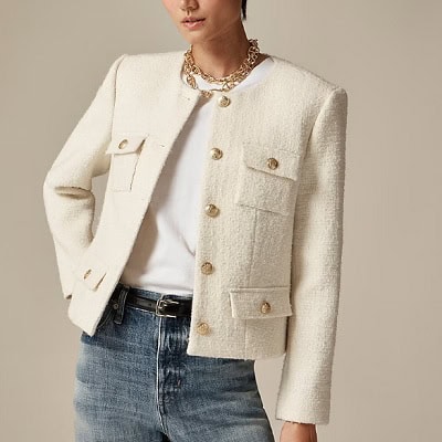 A woman wearing a white inner blouse with cream tweed blazer top and denim pants