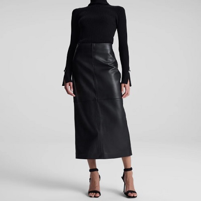 A woman wearing a black turtleneck long and black leather skirt and sandals